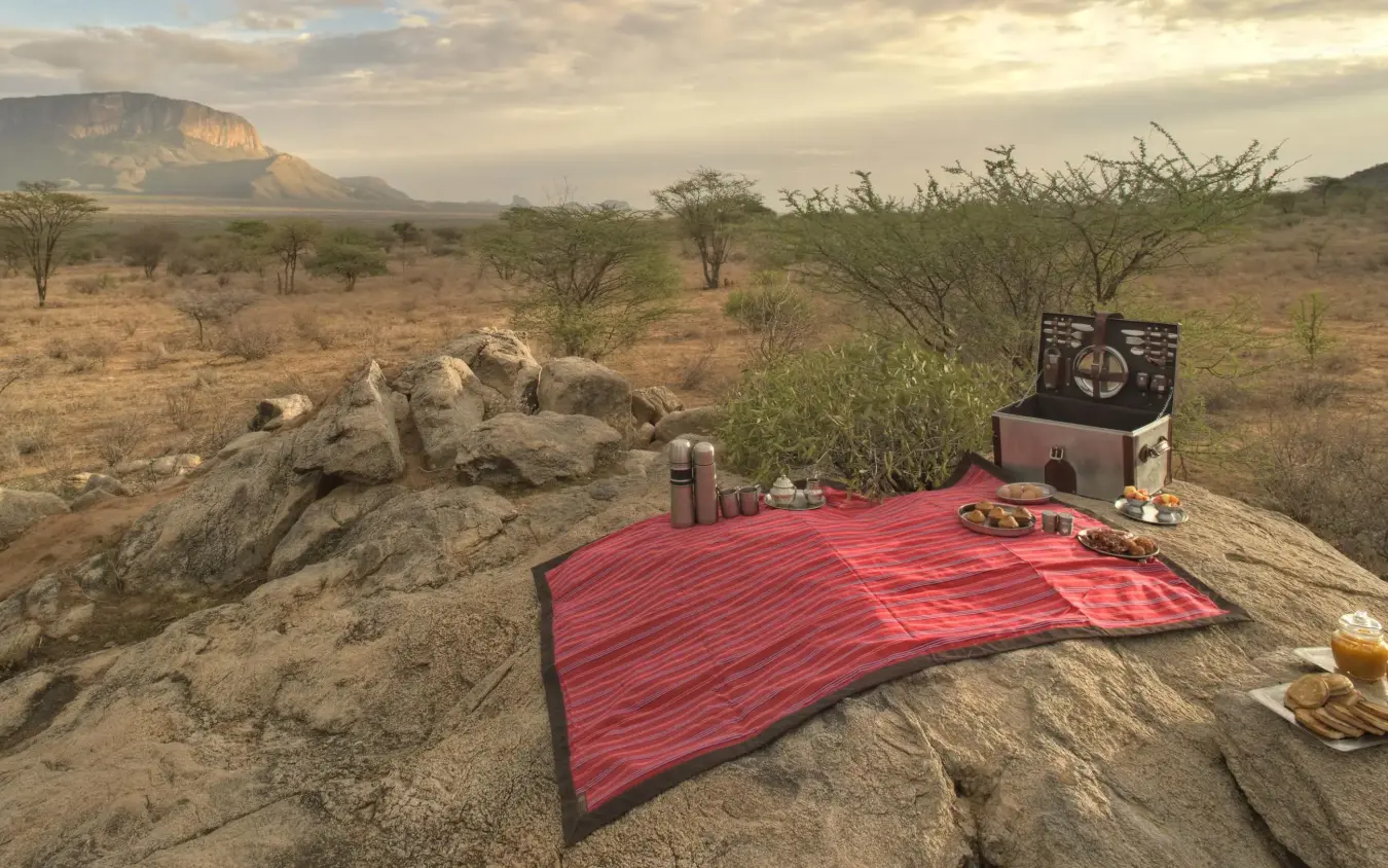 Outdoor dining setup on rocky outcrop with mountain view, Saruni Samburu, Samburu Reserve, Kenya