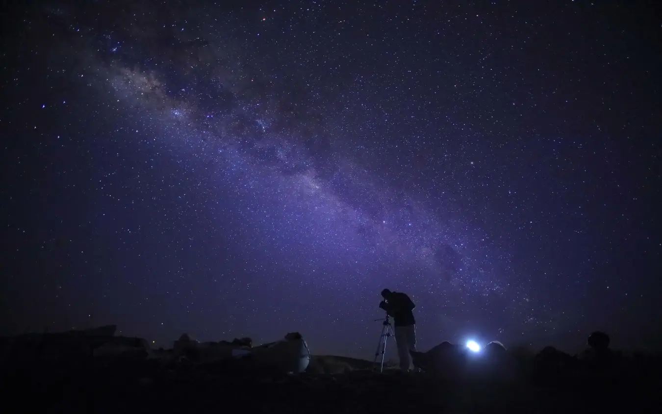 Astronomer observing night sky with telescope under Milky Way, Saruni Samburu, Samburu Reserve, Kenya