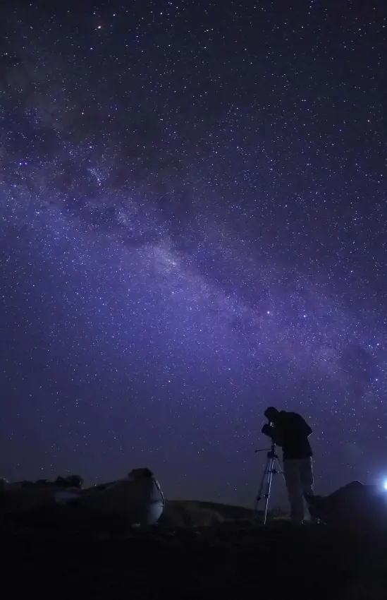 Astronomer observing night sky with telescope under Milky Way, Saruni Samburu, Samburu Reserve, Kenya