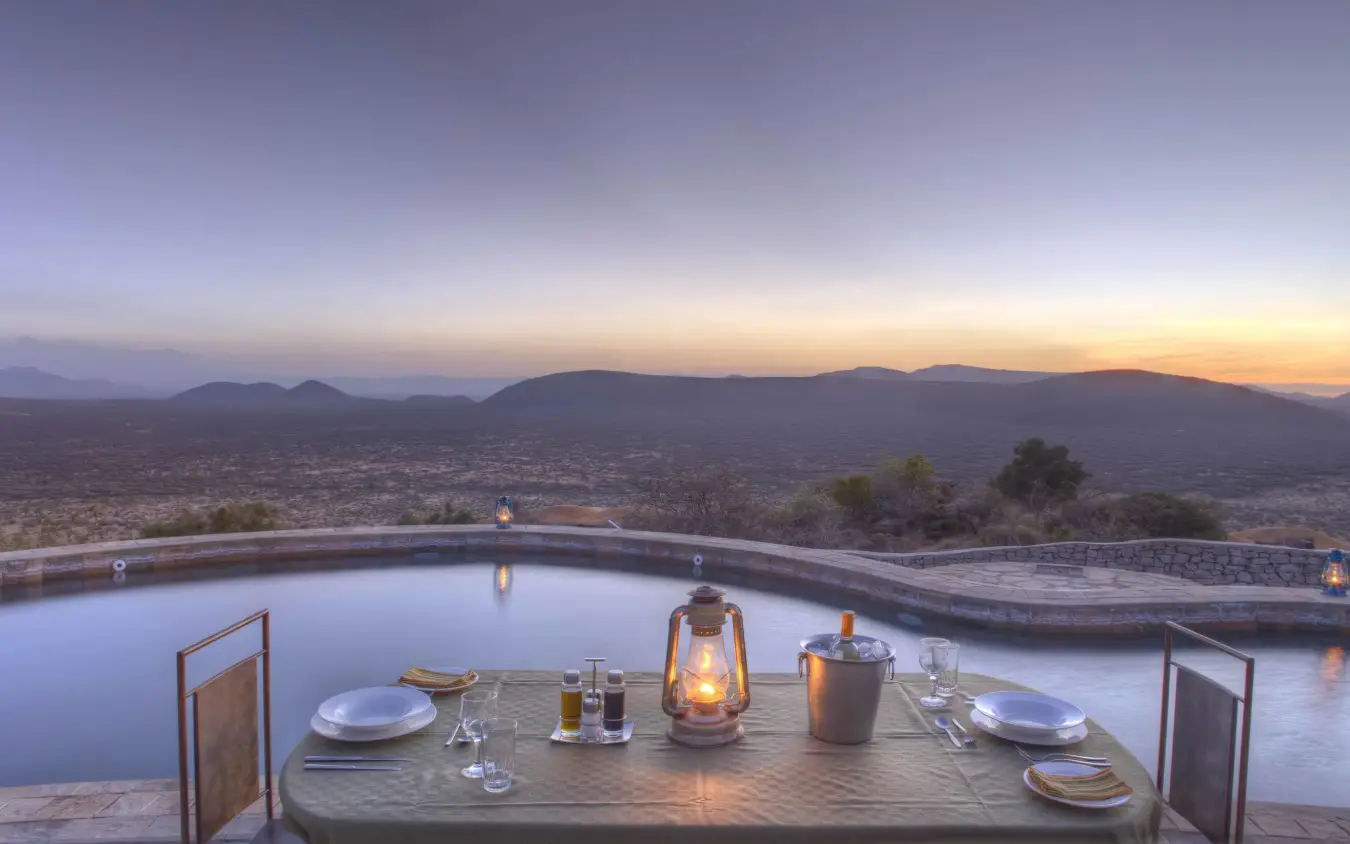 Dining table set beside infinity pool overlooking city valley, Saruni Samburu, Samburu Reserve, Kenya
