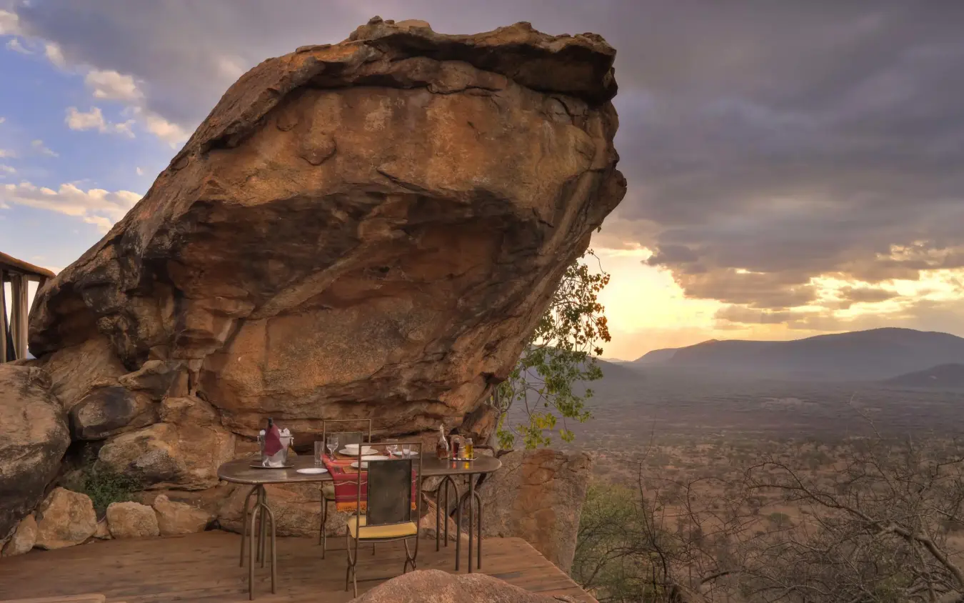 Wooden deck dining area beneath massive balanced rock formation, Saruni Samburu, Samburu Reserve, Kenya
