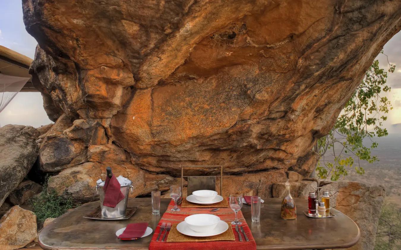 Dining table set under massive natural rock outcrop, Saruni Samburu, Samburu Reserve, Kenya