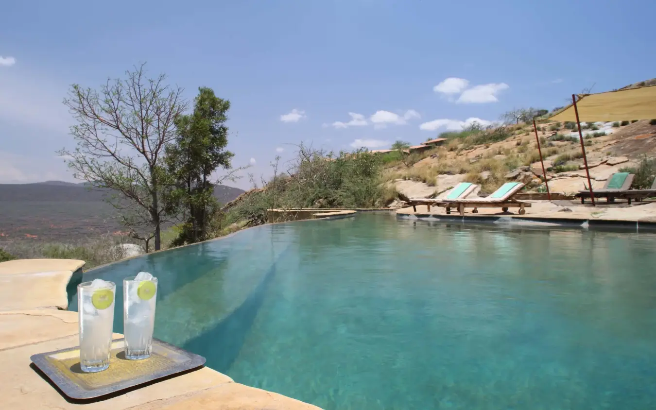 Infinity pool overlooking arid valley landscape with lounge chairs, Saruni Samburu, Samburu Reserve, Kenya