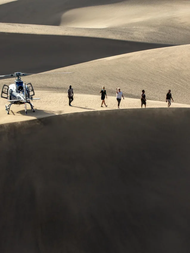 Helicopter landing in desert with group of people walking, Sasaab, Samburu Reserve, Kenya