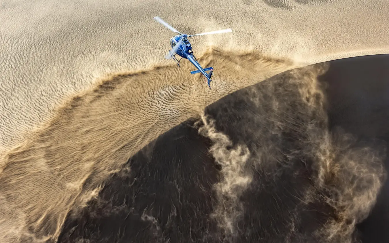 Helicopter flying over desert dunes and rock formations, Sasaab, Samburu Reserve, Kenya