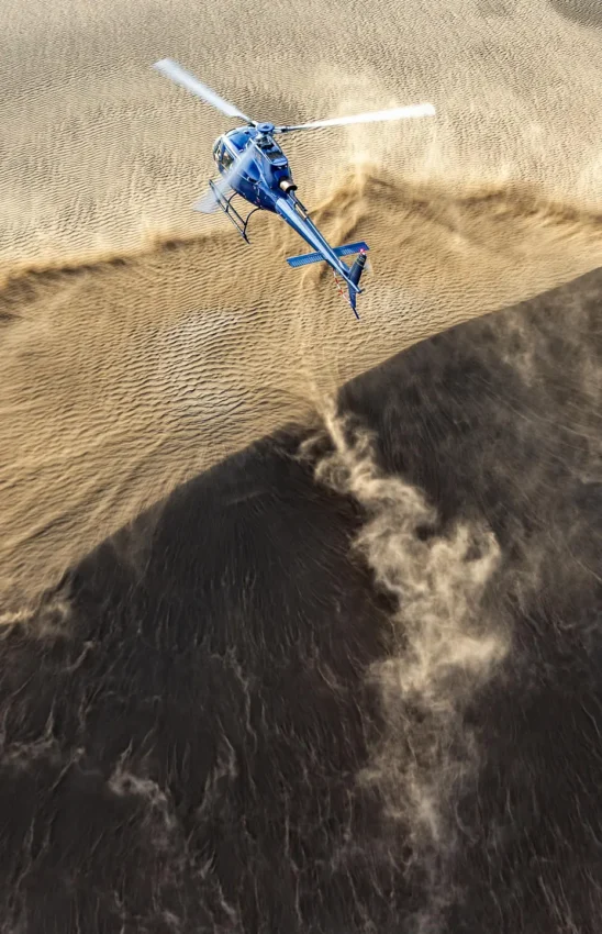 Helicopter flying over desert dunes and rock formations, Sasaab, Samburu Reserve, Kenya