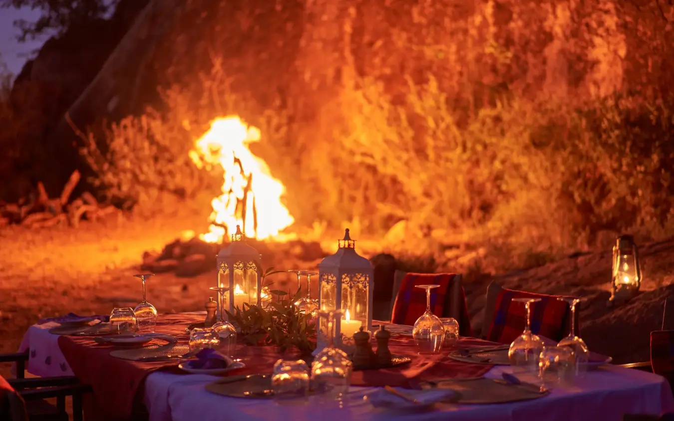 Evening dinner setup with bonfire and candlelit table, Sasaab, Samburu Reserve, Kenya
