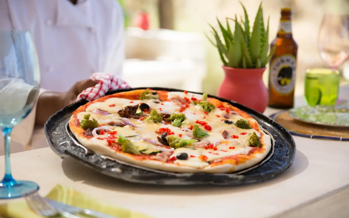 Pizza served on cast iron plate at outdoor dining table, Sasaab, Samburu Reserve, Kenya