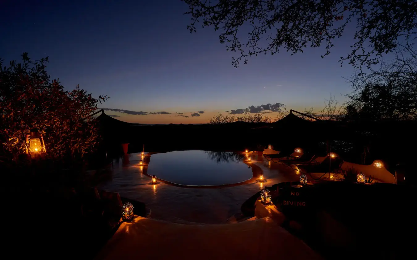 Illuminated circular pool at dusk with desert landscape, Sasaab, Samburu Reserve, Kenya