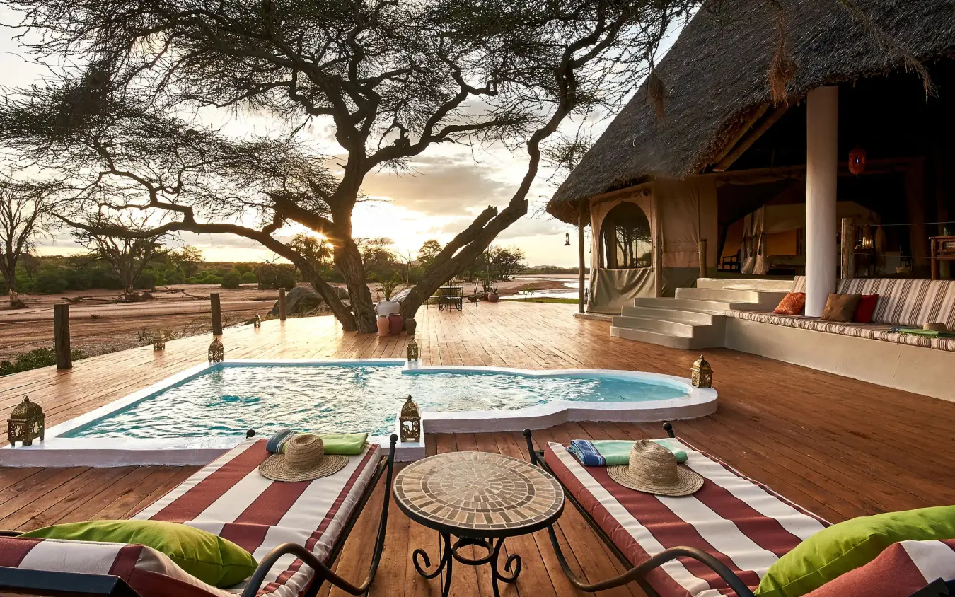 Riverside pool deck with lounge chairs and thatched lodge, Sasaab, Samburu Reserve, Kenya