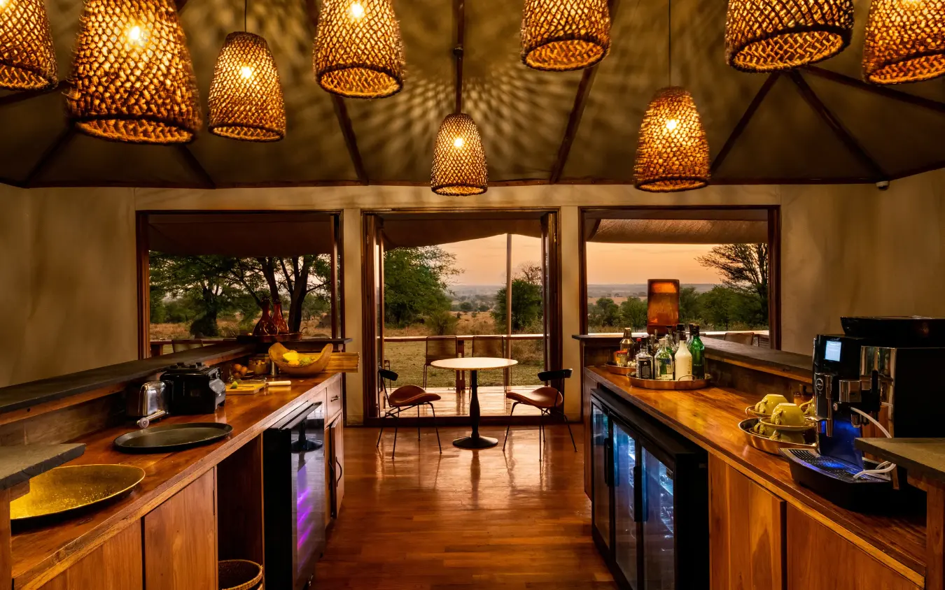 Open-air lounge with wooden counters and pendant lighting overlooking savanna, Sayari Camp, Serengeti National Park, Tanzania