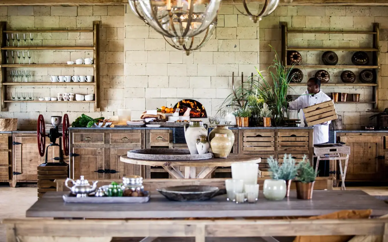 Open kitchen with wood counters, hanging lights, and staff, Segera, Laikipia Highlands, Kenya