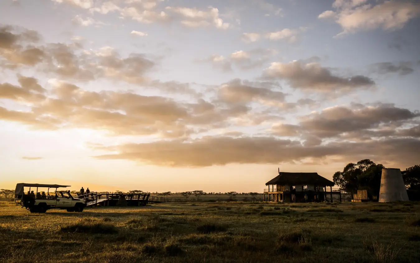 Safari vehicle parked near homestead at golden hour sunset, Segera, Laikipia Highlands, Kenya