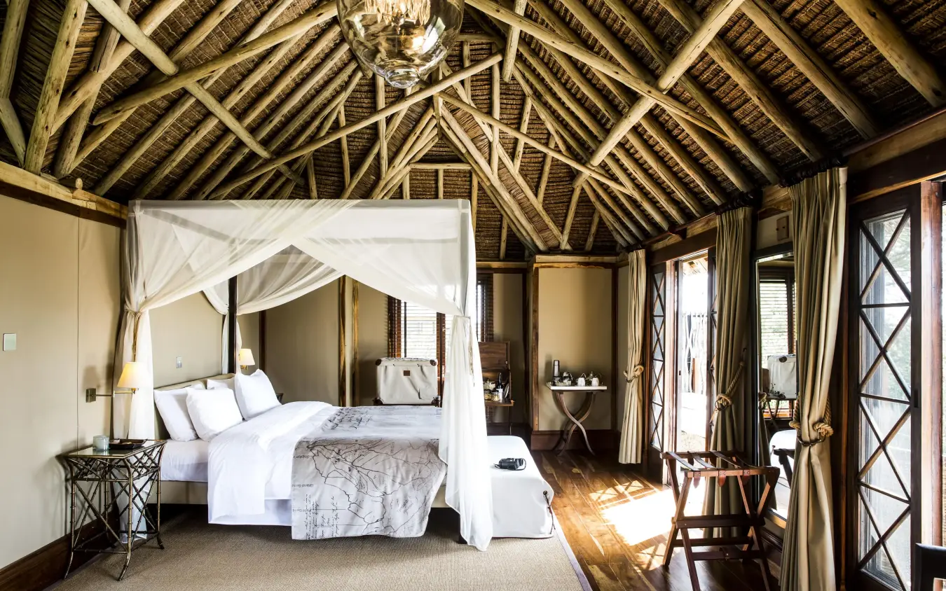 Spacious bedroom with four-poster bed and exposed wooden beams, Segera, Laikipia Highlands, Kenya