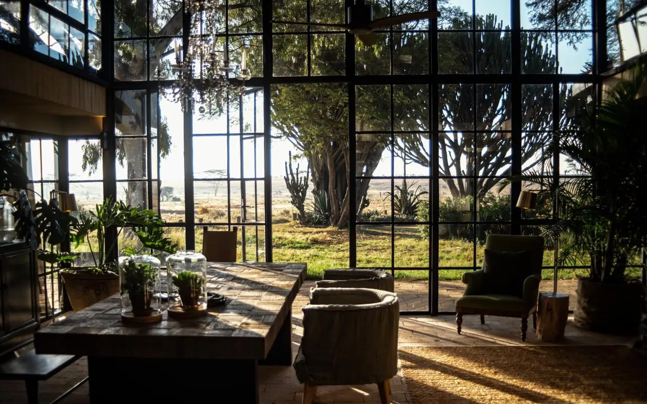 Interior lounge with floor-to-ceiling windows overlooking savanna landscape, Segera, Laikipia Highlands, Kenya