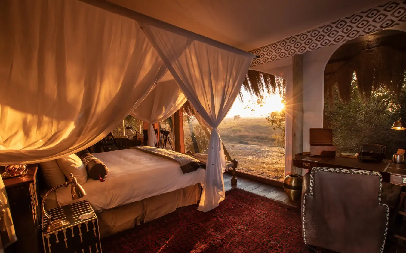 Luxury bedroom tent with draped canopy overlooking savanna landscape, Selinda Camp, Selinda Reserve, Botswana