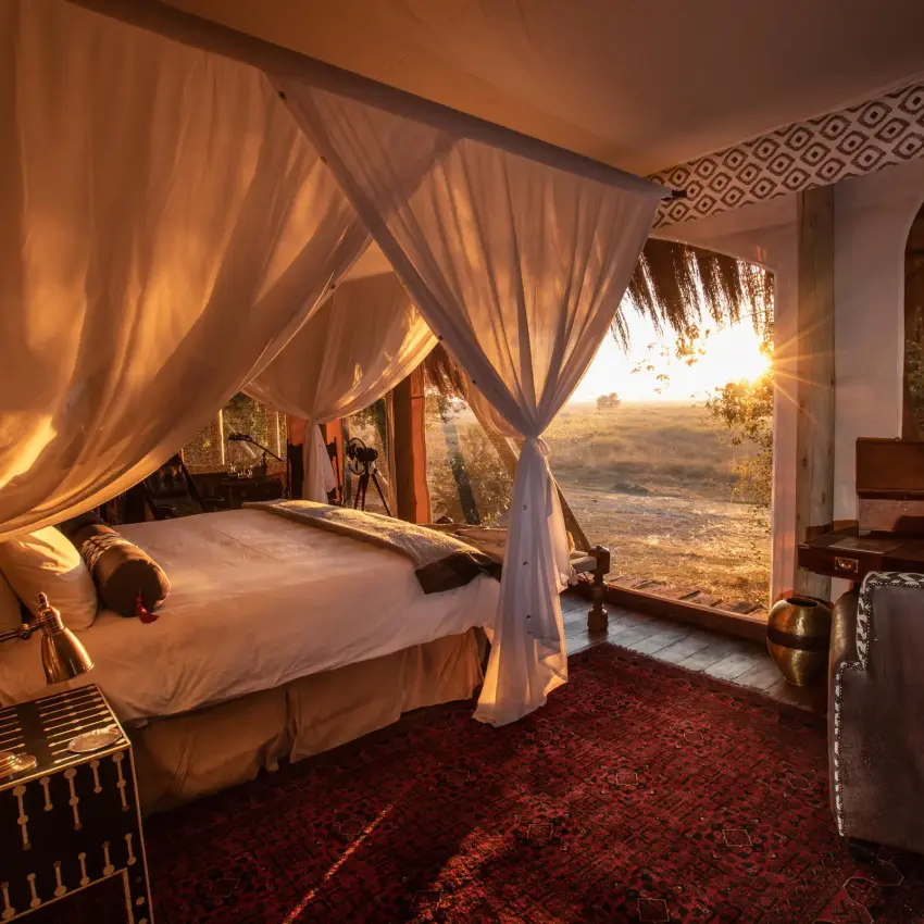 Luxury bedroom tent with draped canopy overlooking savanna landscape, Selinda Camp, Selinda Reserve, Botswana