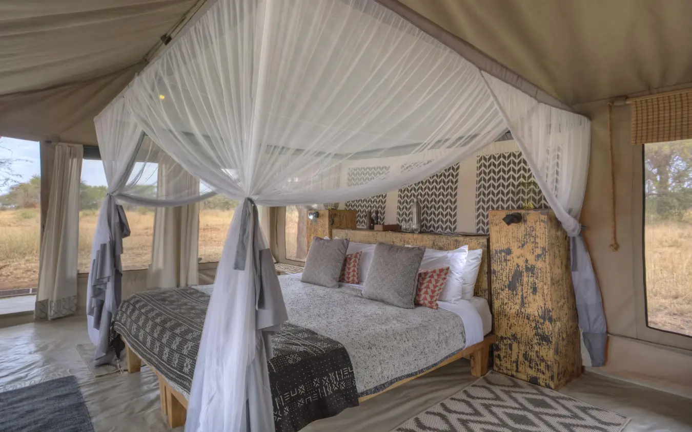 Canvas tent bedroom with four-poster bed and savanna views, Ubuntu Migration Camp, Serengeti National Park, Tanzania