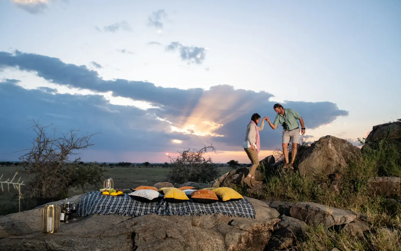 Couple stargazing on rocky outcrop at sunset, Tanzania