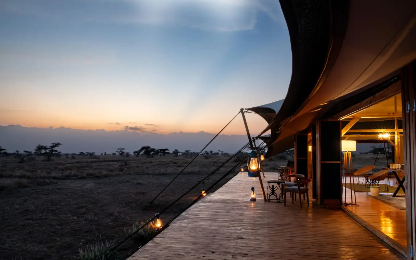 Wooden deck overlooking savanna at sunset with lanterns, Serengeti Plains Camp, Serengeti National Park, Tanzania