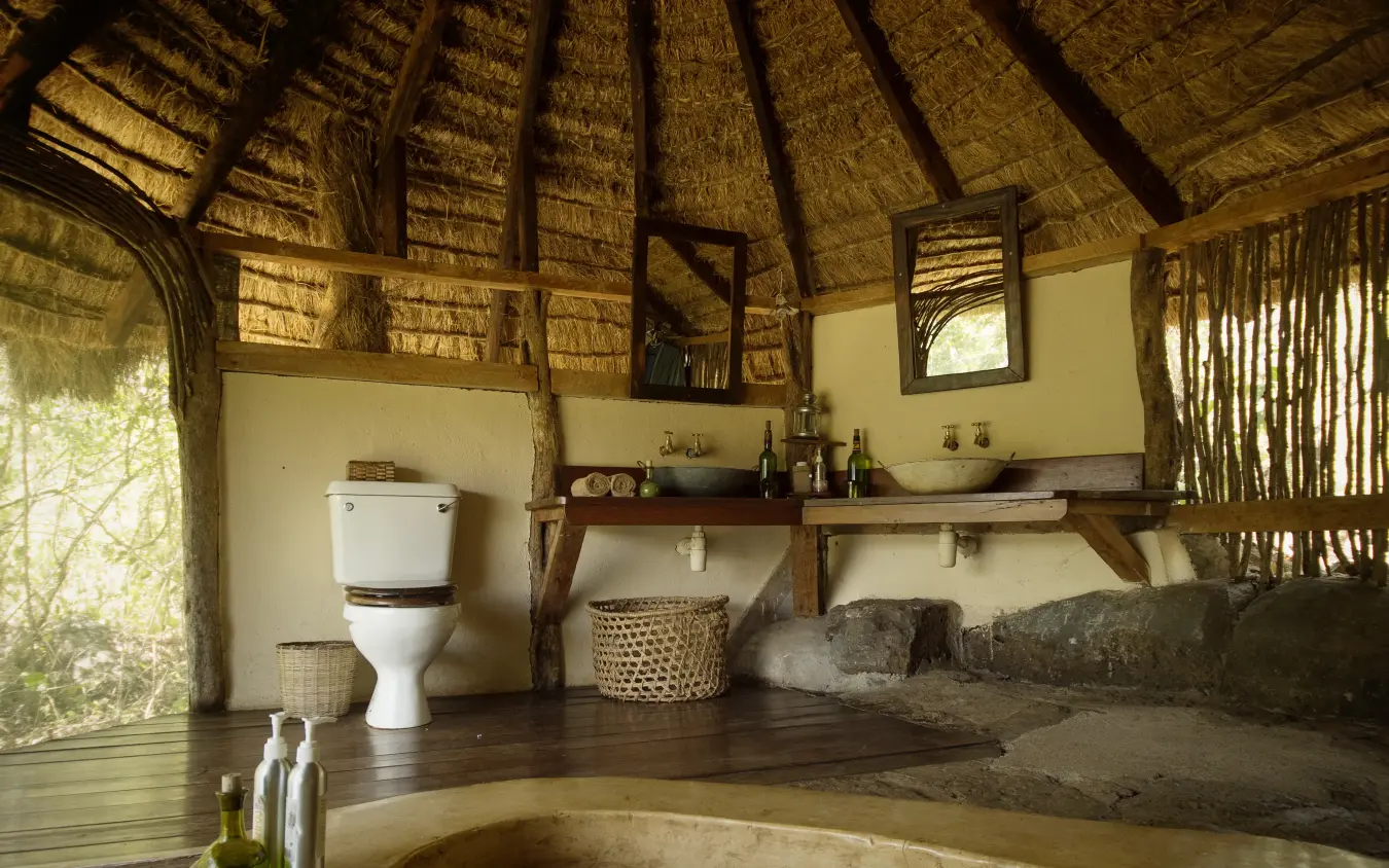 Round thatched bathroom with stone bathtub and fixtures, Serian “The Original”, Maasai Mara, Kenya