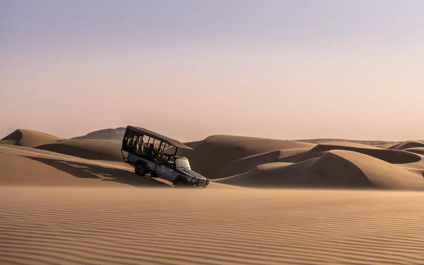 Four-wheel drive vehicle navigating large desert sand dunes, Serra Cafema, Kunene River, Namibia