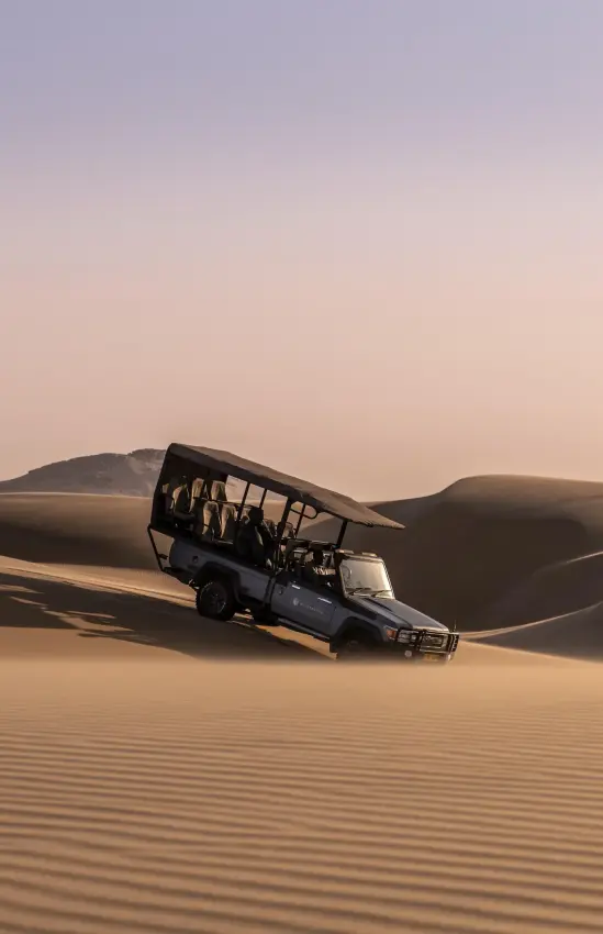 Four-wheel drive vehicle navigating large desert sand dunes, Serra Cafema, Kunene River, Namibia
