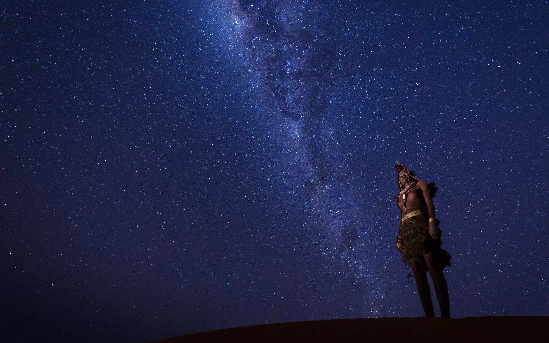 Person stargazing under Milky Way at night, Serra Cafema, Kunene River, Namibia