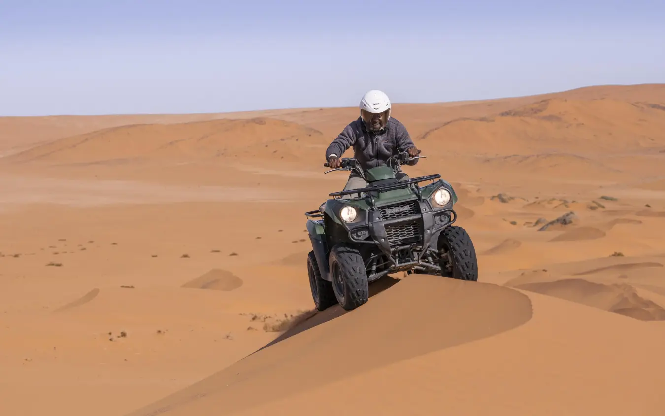 Guest riding quad bike across sand dunes, Serra Cafema, Kunene River, Namibia