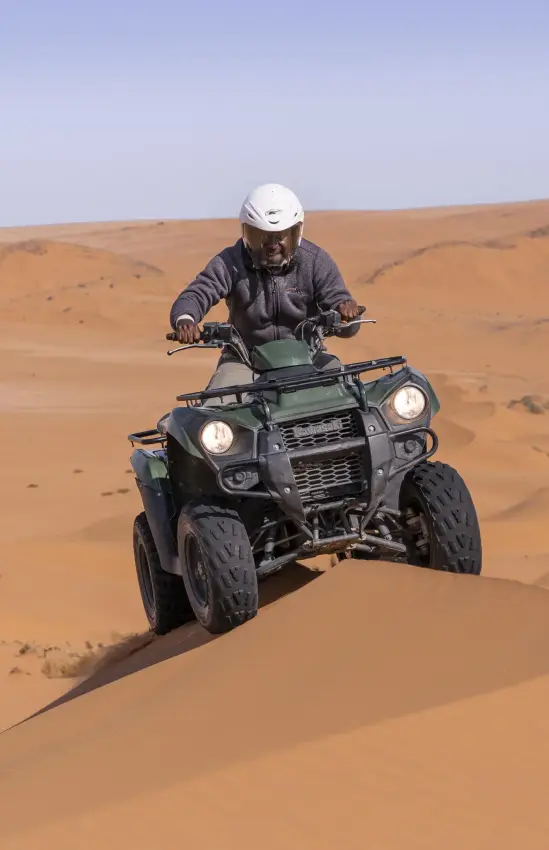 Guest riding quad bike across sand dunes, Kunene River, Namibia