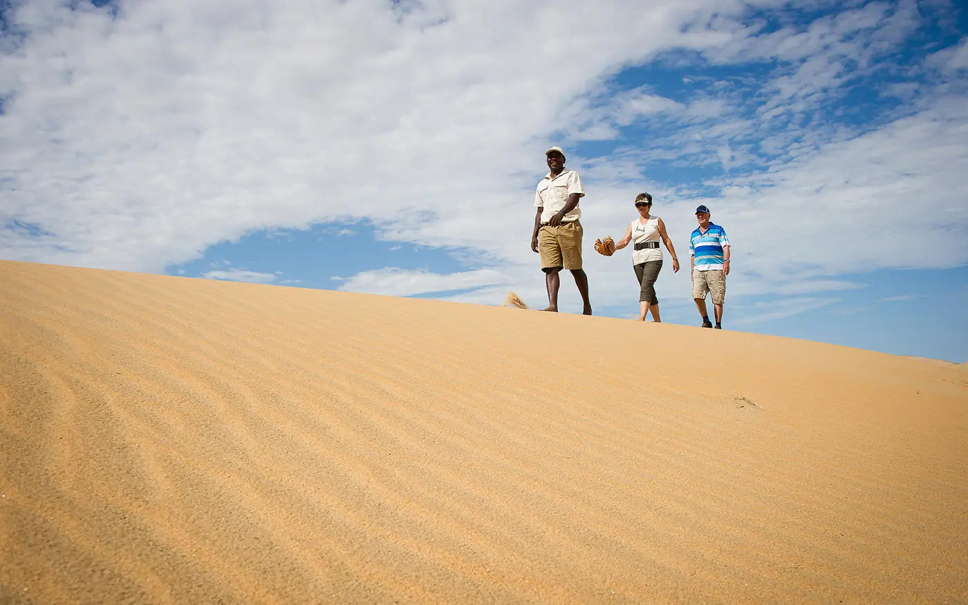 Guests walking and playing basketball on sand dune, Namibia