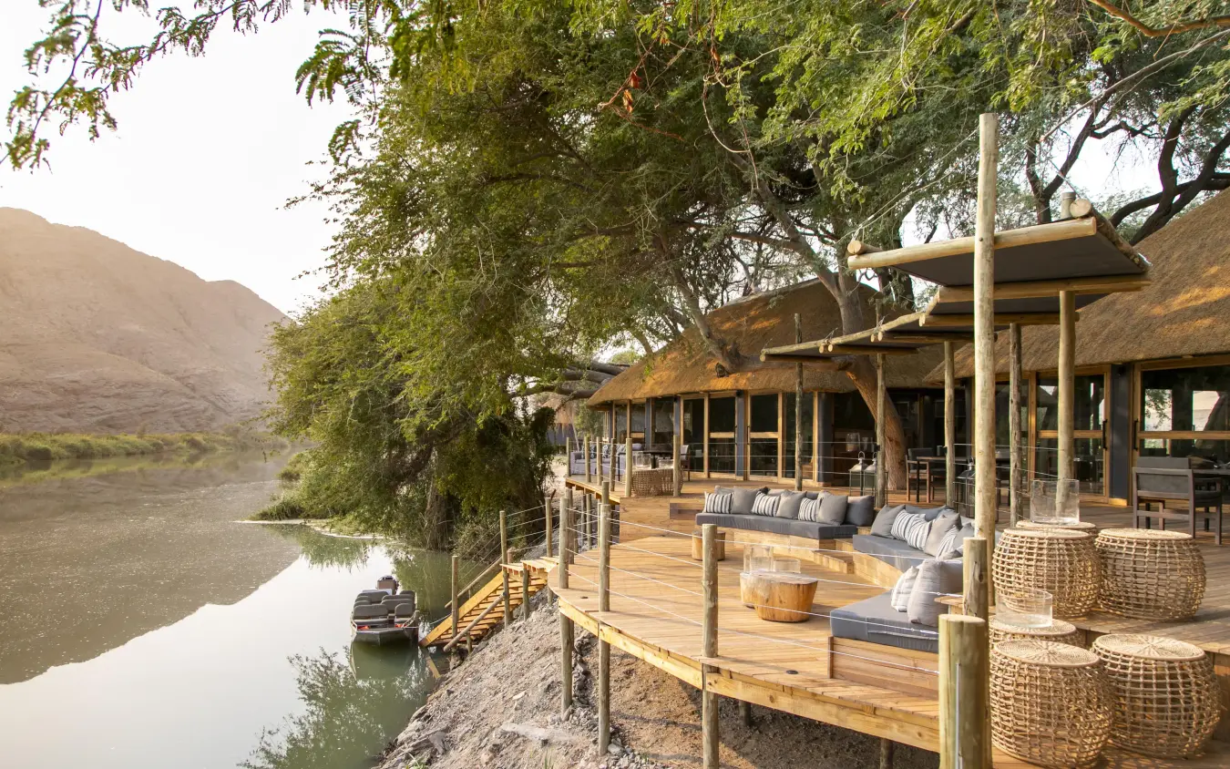 Wooden deck overlooking river with thatched structures, Serra Cafema, Kunene River, Namibia