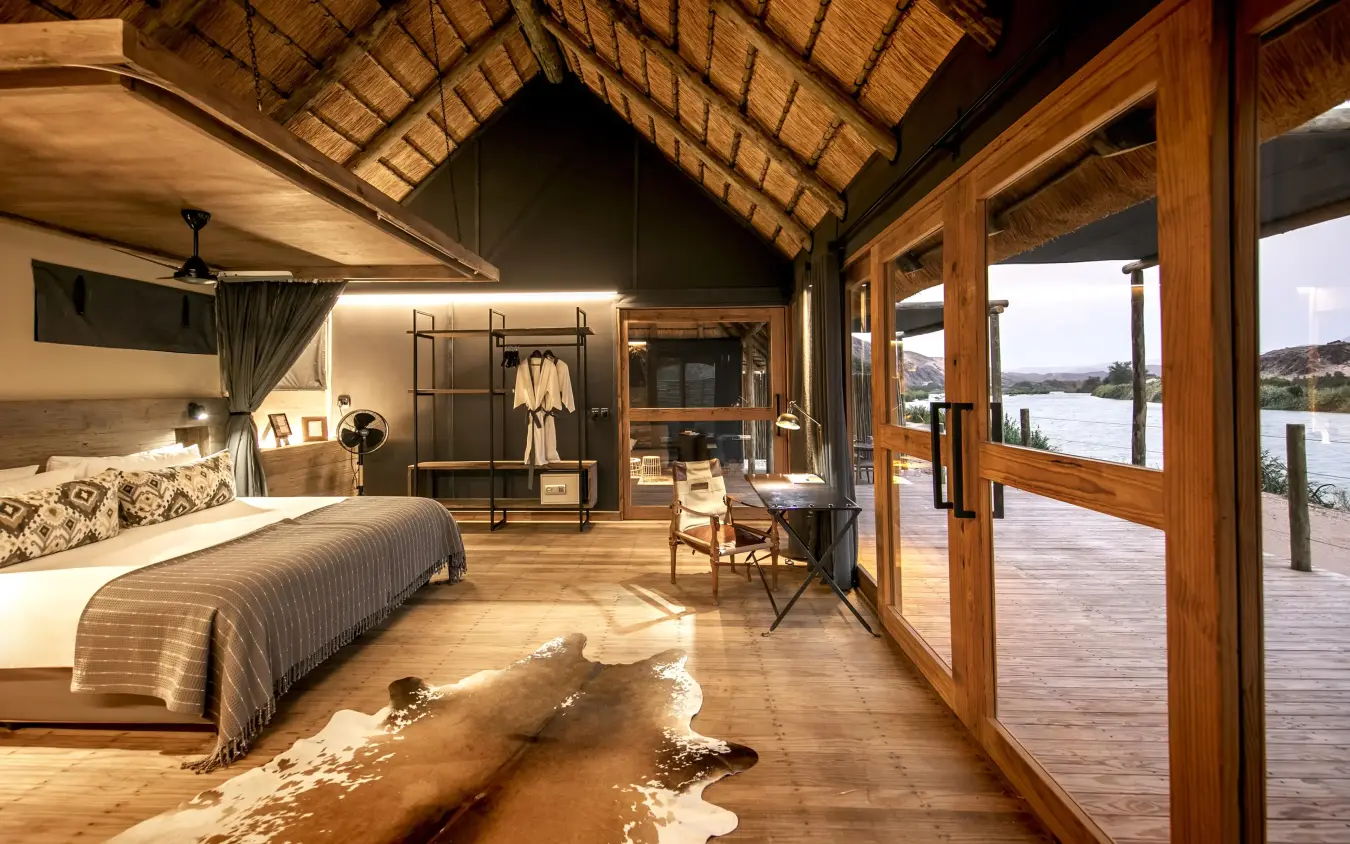 Luxury bedroom with wooden deck overlooking river, Serra Cafema, Kunene River, Namibia