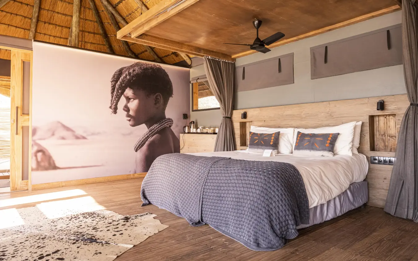Spacious bedroom with thatched roof and desert artwork, Serra Cafema, Kunene River, Namibia