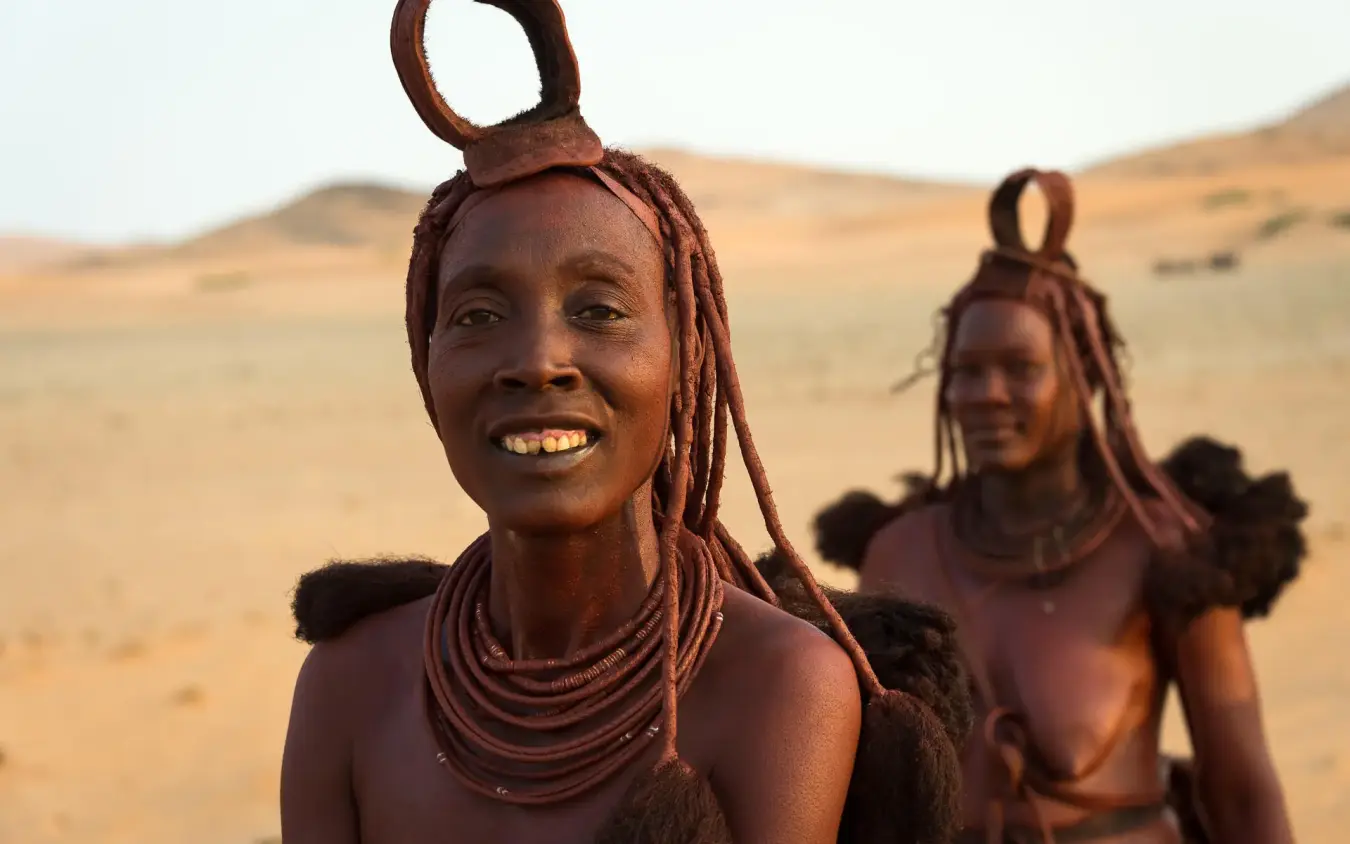 Himba women with traditional hairstyles in desert landscape, Serra Cafema, Kunene River, Namibia