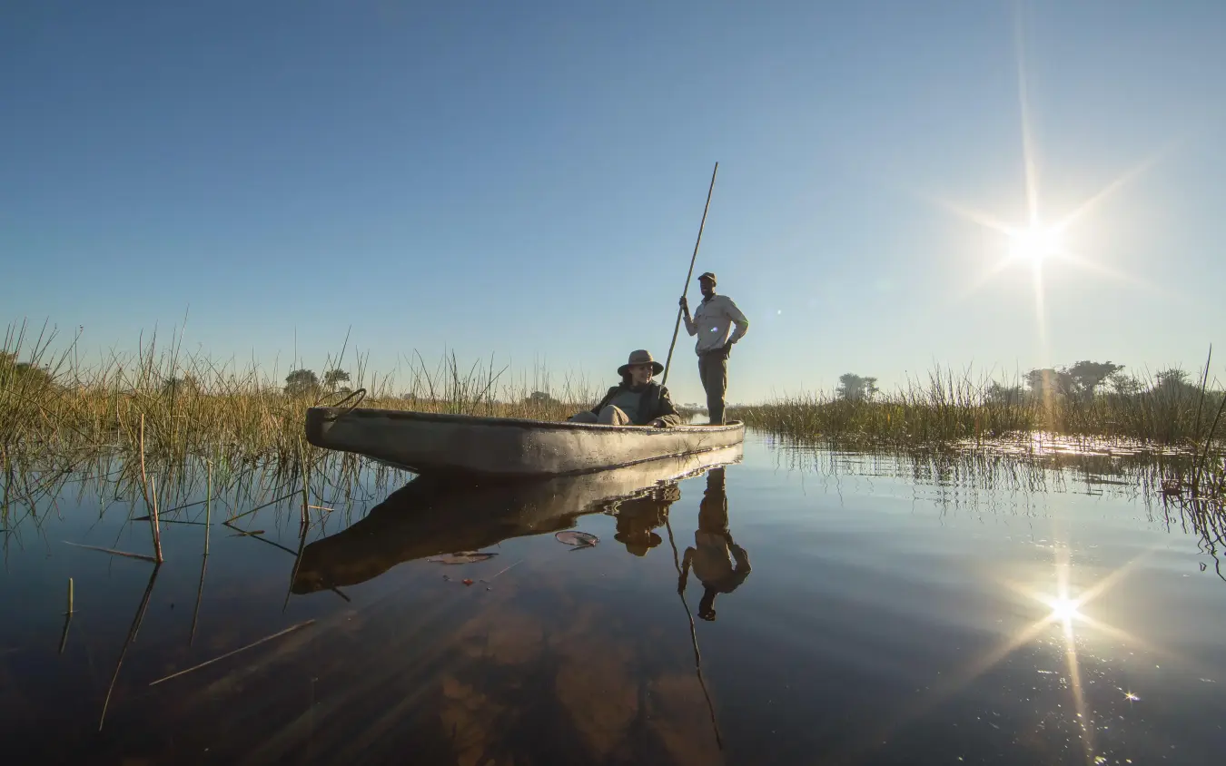 Poling traditional boat through shallow water channels, Setari, The Okavango Delta, Botswana