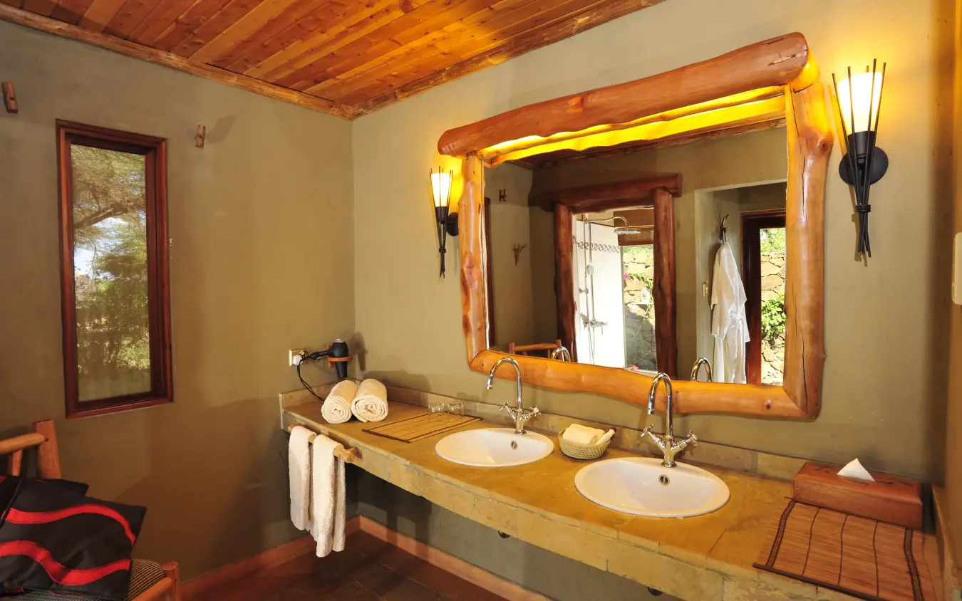 Luxury bathroom with double vanity, wooden beams, and large mirror, Severin Safari Camp, Tsavo, Kenya