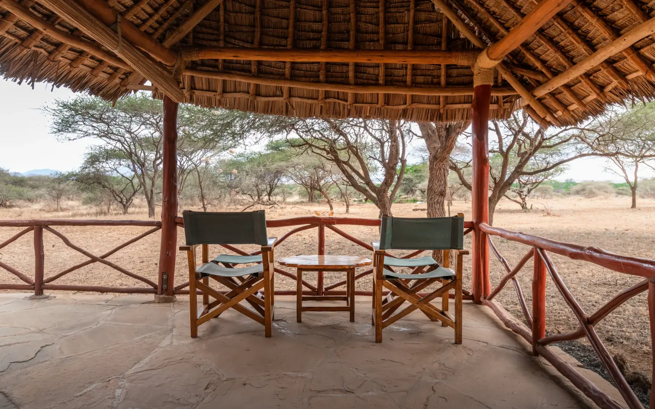 Thatched gazebo with director chairs overlooking dry savanna woodland, Severin Safari Camp, Tsavo, Kenya