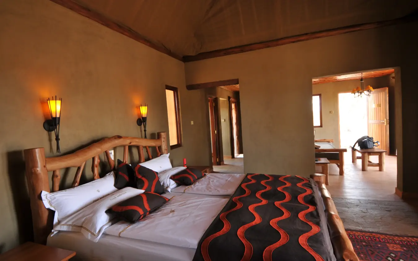 Luxury bedroom suite with wooden furniture and decorative patterned bedding, Severin Safari Camp, Tsavo, Kenya