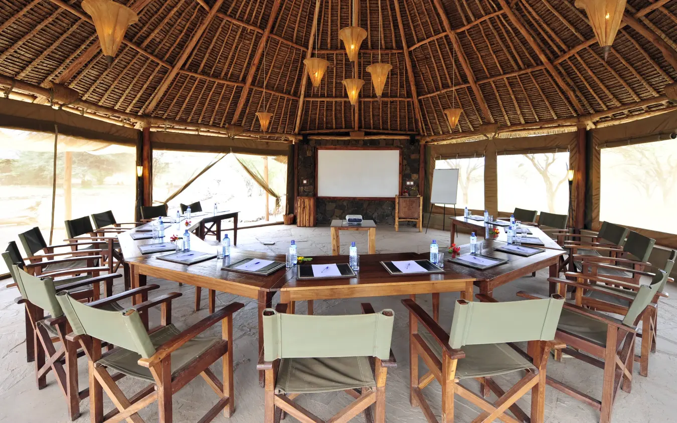 Large circular safari lodge interior with meeting table and canvas tent visible through windows, Severin Safari Camp, Tsavo, Kenya