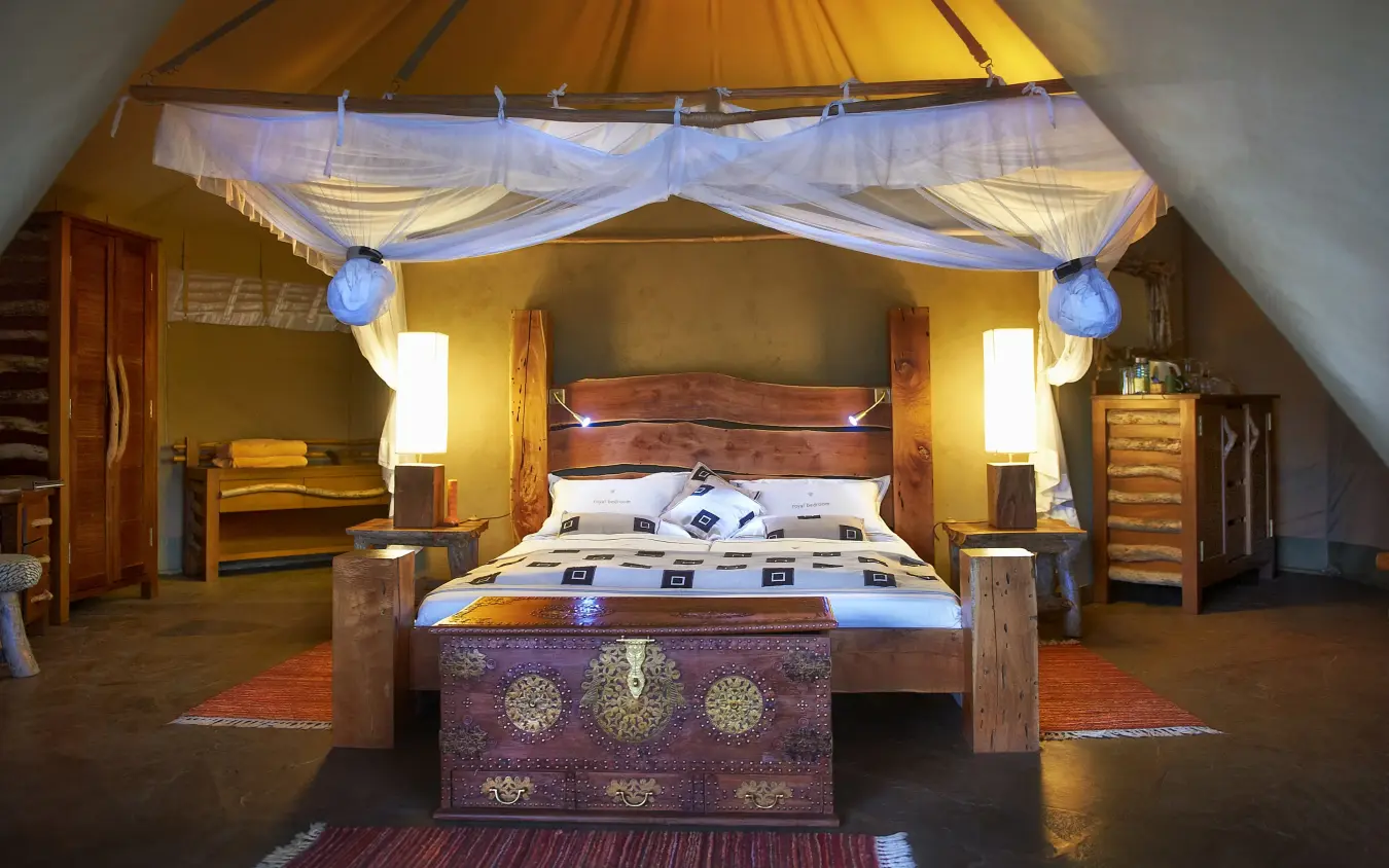 Luxury safari lodge bedroom with canopy bed and golden ochre walls, Severin Safari Camp, Tsavo, Kenya