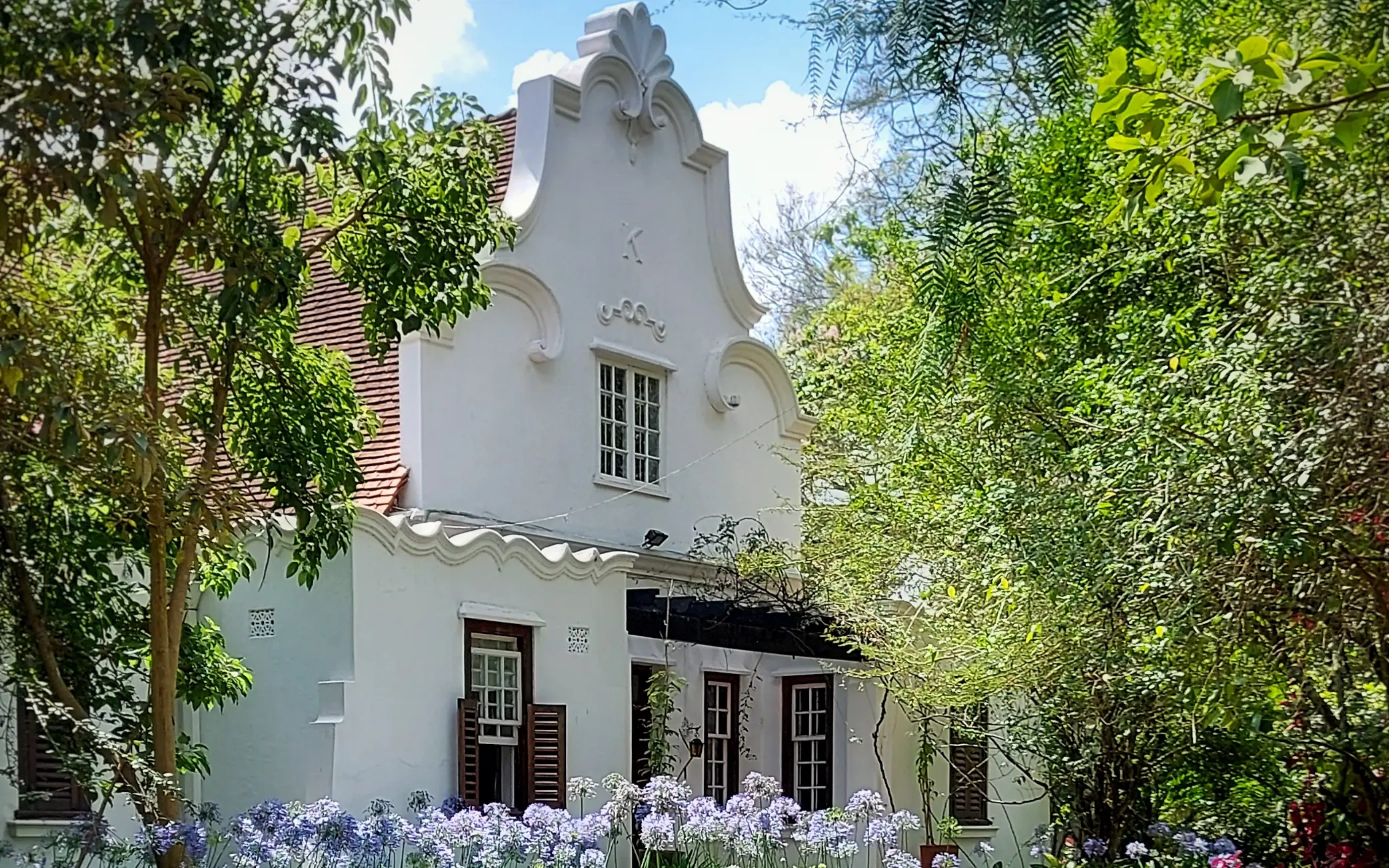 White tower building with gardens and mature trees, Sheba’s Secret Garden, Nairobi, Kenya