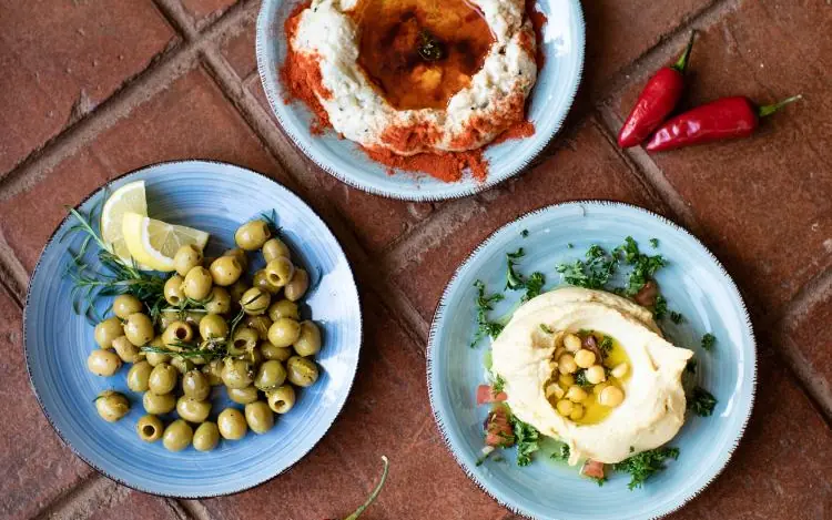Three plates of Middle Eastern mezze appetizers on brick, Sheba’s Secret Garden, Nairobi, Kenya