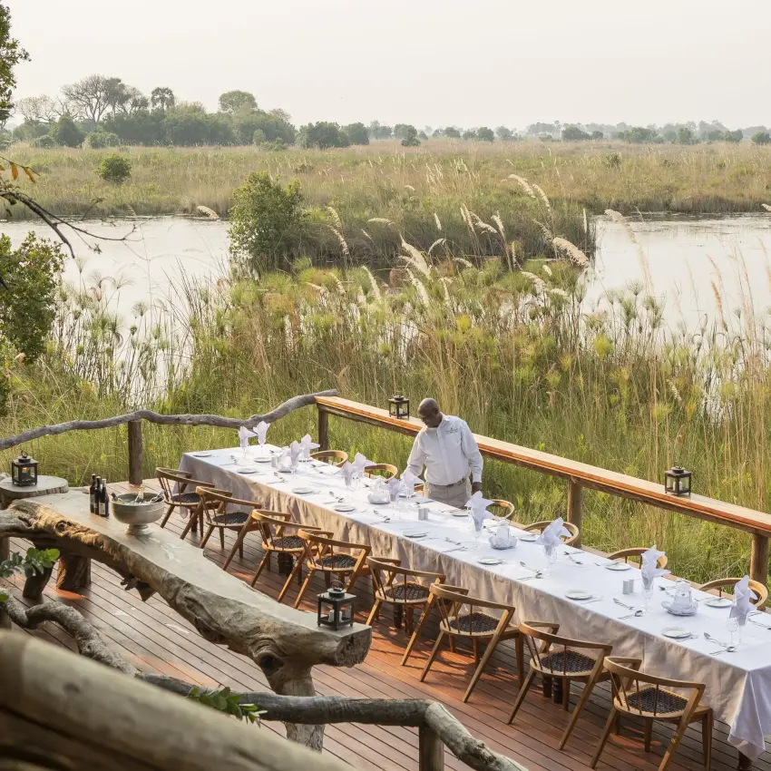 Dining deck overlooking wetland with reeds and water, Shinde, The Okavango Delta, Botswana