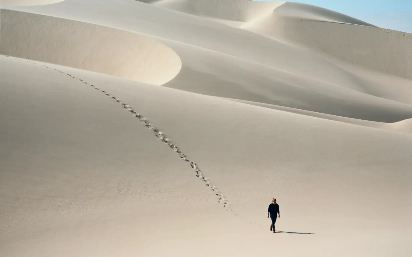 Solitary person walking across white sand dunes, Shipwreck Lodge, Skeleton Coast, Namibia
