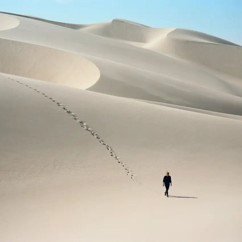 Solitary person walking across white sand dunes, Skeleton Coast, Namibia