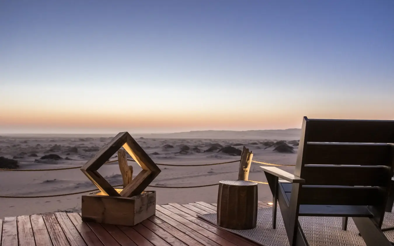 Wooden deck with sculptures overlooking beach at sunset, Shipwreck Lodge, Skeleton Coast, Namibia