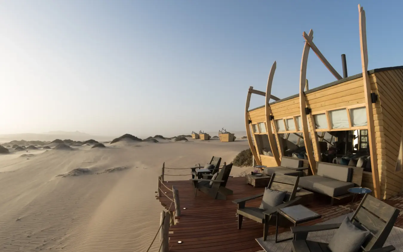 Wooden deck with lounge chairs overlooking vast beach, Shipwreck Lodge, Skeleton Coast, Namibia