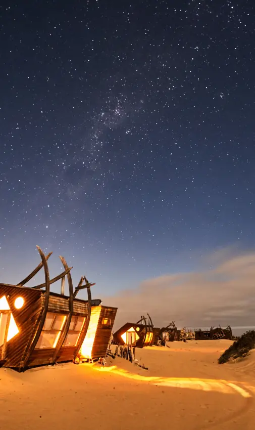 Illuminated lodge structure in desert at night under stars, Shipwreck Lodge, Skeleton Coast, Namibia