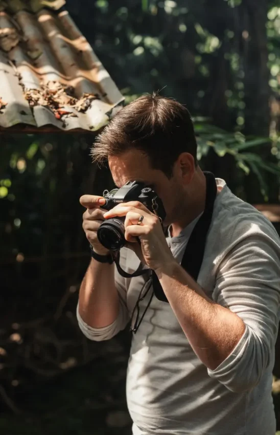 Photographer with camera capturing wildlife in dappled forest light, Silverback Lodge, Bwindi Impenetrable Forest, Uganda